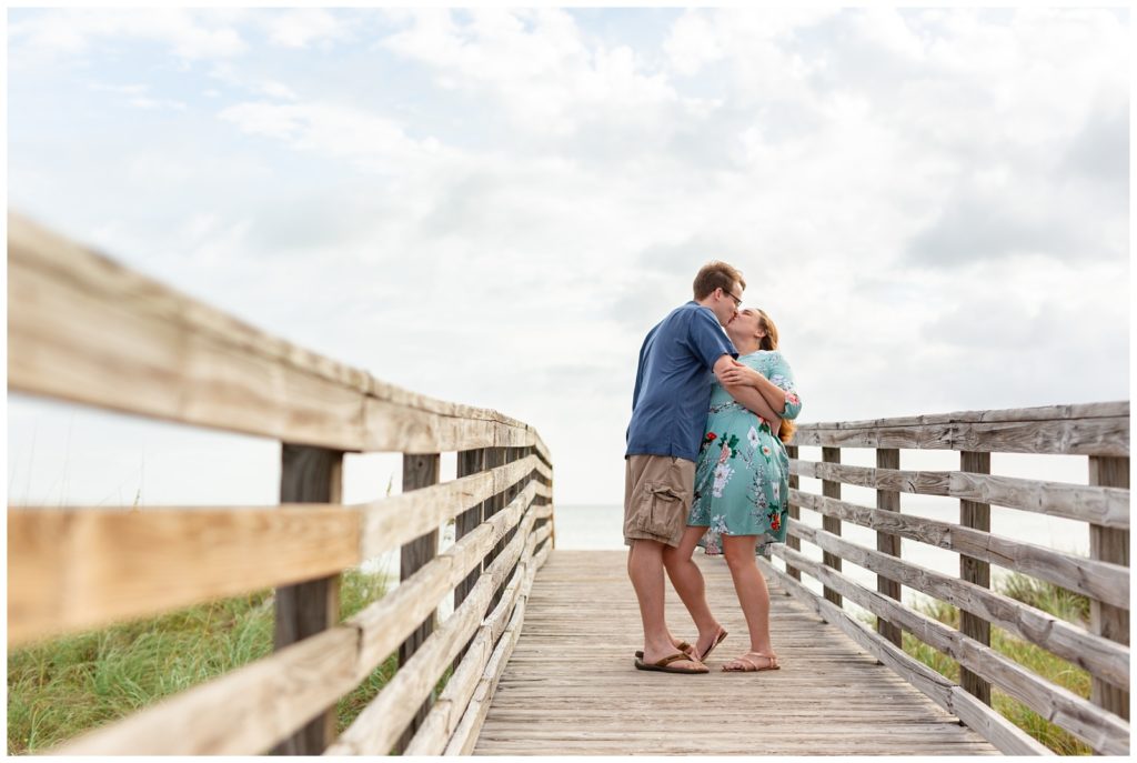 Photo of engaged couple kissing on a pier at Honeymoon Island in Dunedin Florida.