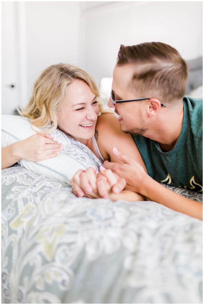 DIY couple in Tampa Florida laying forward on bed laughing with one another.