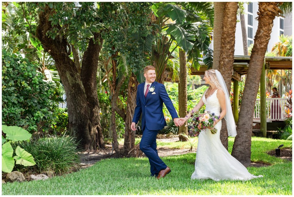 Groom Holding his brides hand and leading her while they walk and smile at one another at Tampa Rusty Pelican wedding