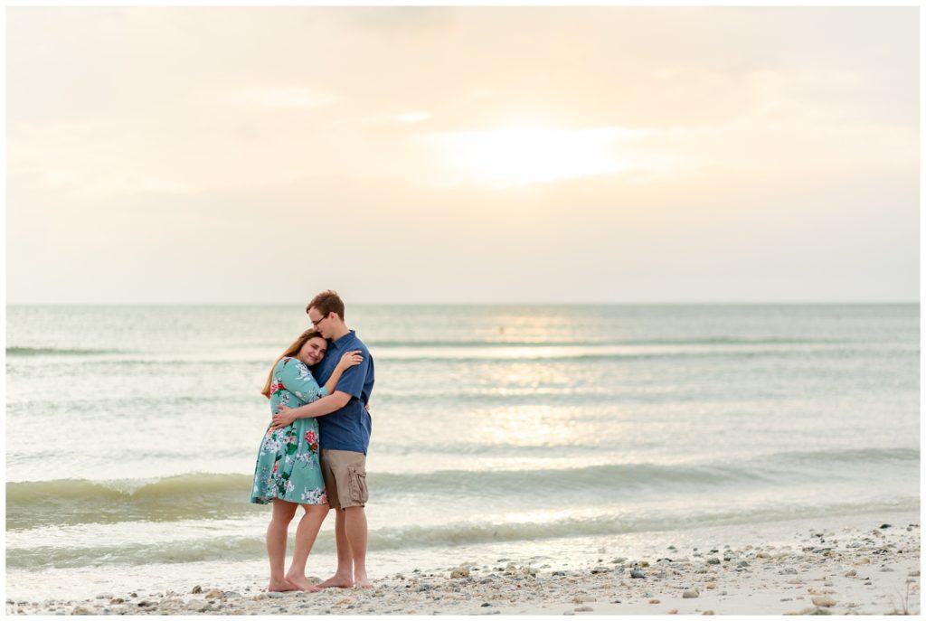 Newly Engaged couple hugging during sunset in the sand at Honeymoon Island in Dunedin, Florida