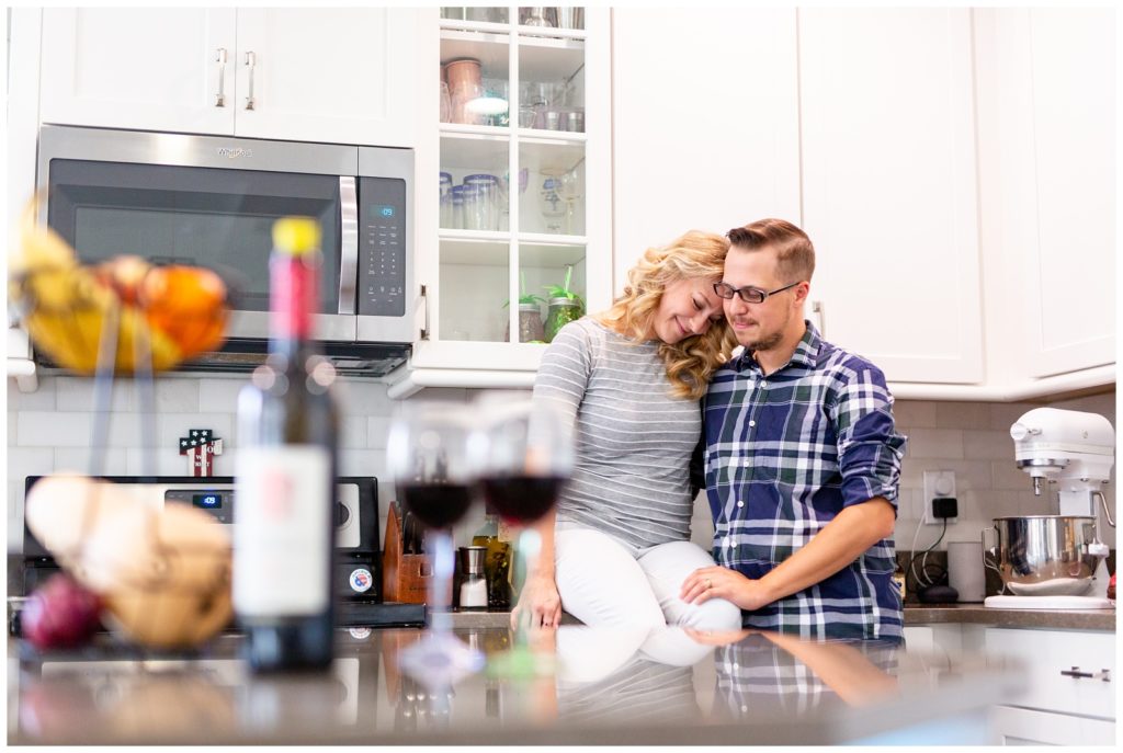 DIY couple sitting on kitchen counter behind a bottle of wine in Tampa, Florida.