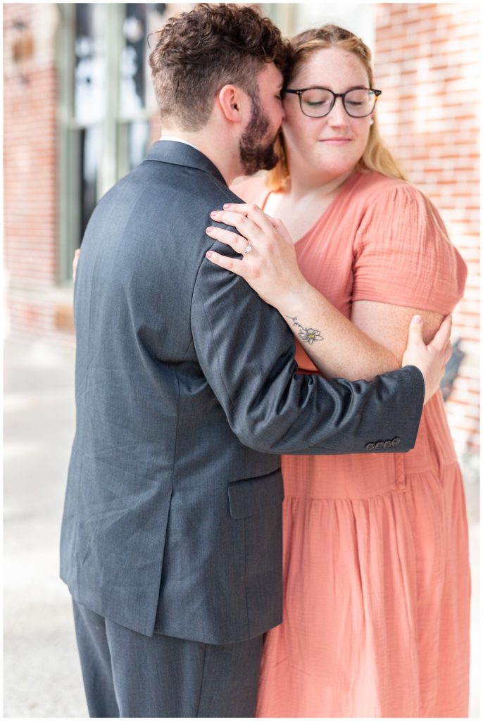 Future groom nuzzling with his fiance in peach dress in Tampa, Florida. 