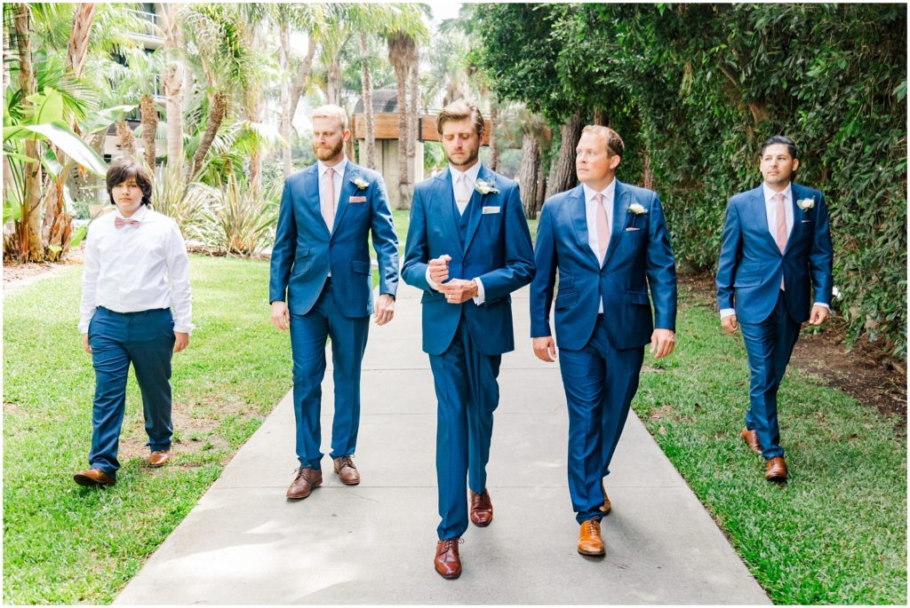 Groom walking with groomsmen in blue suits on wedding day