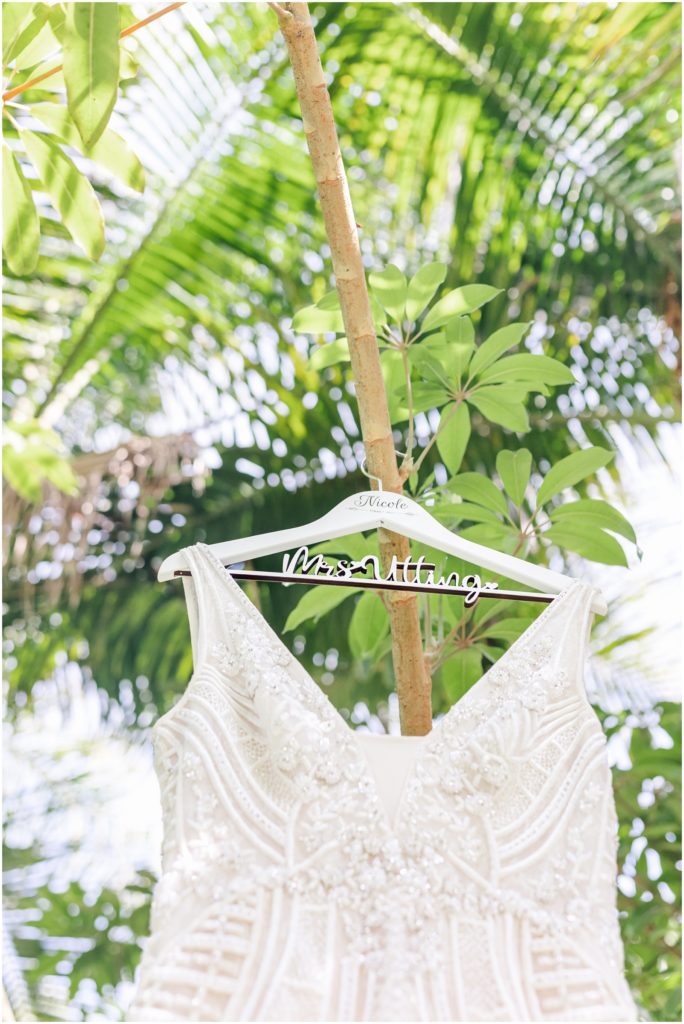 Wedding dress hanging on customized Mrs. with tropical green palm trees in the background