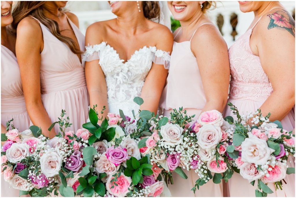 Close up photo of bride and bridesmaids holding their bouquets with pink and purple florals